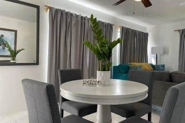 A modern living room with a round table, grey sofas, and a potted plant.