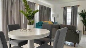 Ein modernes Wohnzimmer mit einem runden Tisch, grauen Sofas und einem 'welcome'-Schild.