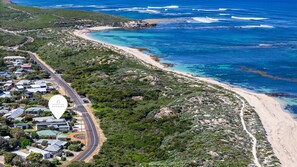 Una zona costera con una carretera serpenteando por un barrio residencial, que desemboca en una playa.