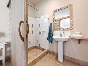 Un baño con ducha, lavabo y espejo.
