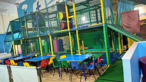 An indoor play area with a netted climbing structure, colorful play tables, and chairs. - 3 bed Static 12ft Caravan Home From Home Somerset (Watchet)
