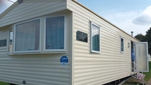 A mobile home with a large window on the left side, a smaller window on the right, and a door on the right side. - 3 bed Static 12ft Caravan Home From Home Somerset (Watchet)