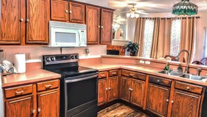 A kitchen with wooden cabinets, a microwave, a stove, and a sink. - A fully furnished home within walking distance of downtown Mansfield (Mansfield)