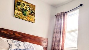 A bed with a patterned bedspread, a wooden headboard, and a painting above it. - A fully furnished home within walking distance of downtown Mansfield (Mansfield)