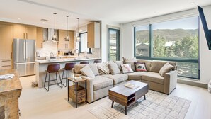 A modern kitchen with a large island, bar stools, and a built-in oven.