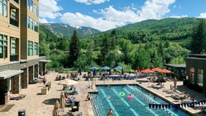 A pool area with multiple lanes, lounge chairs, and umbrellas.