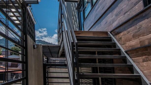 Un bâtiment moderne avec un escalier menant à un étage supérieur, de grandes fenêtres et un ciel bleu dégagé.