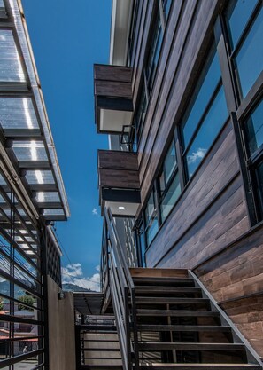 A modern building with a staircase leading to an upper level, large windows, and a clear blue sky. - The Stay (San José)