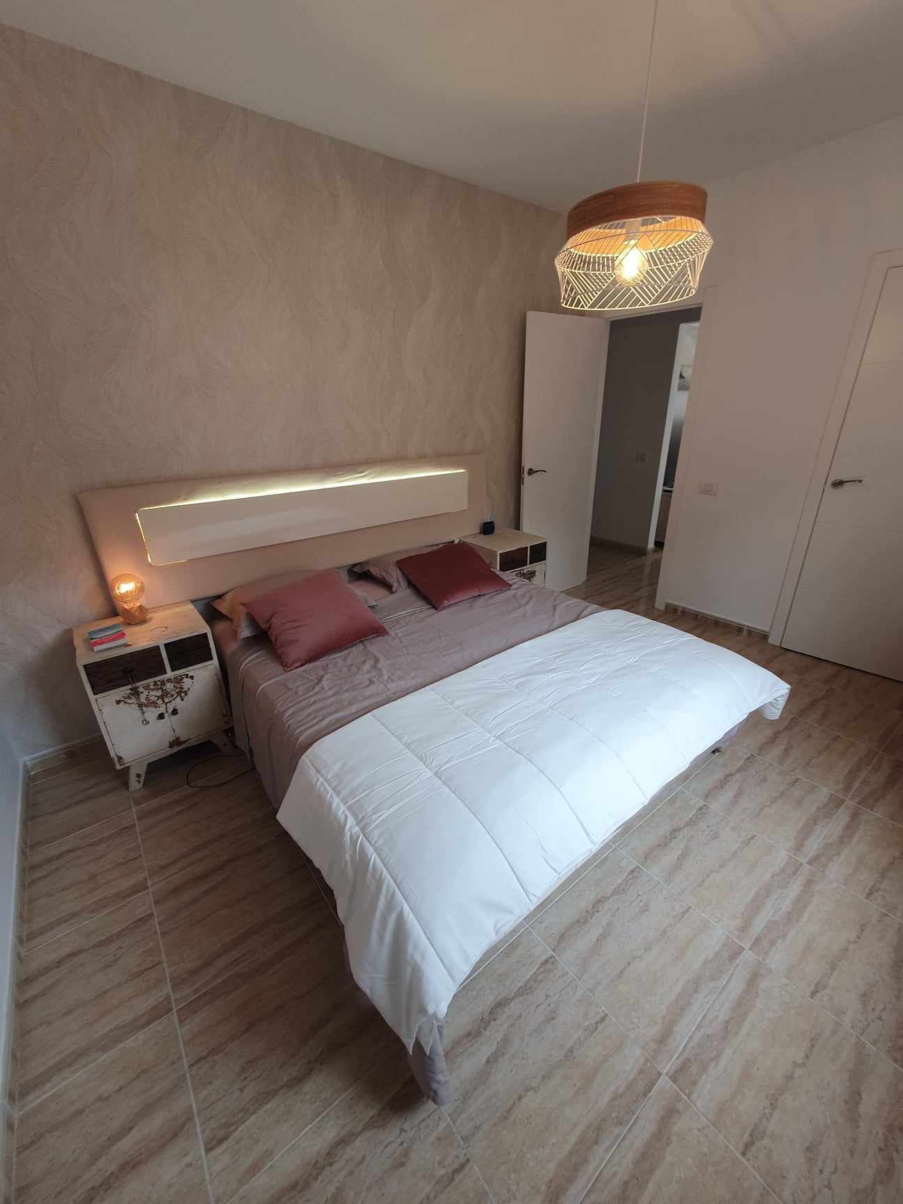 Een slaapkamer met een bed, nachtkastjes, een hanglamp en een kledingkast.