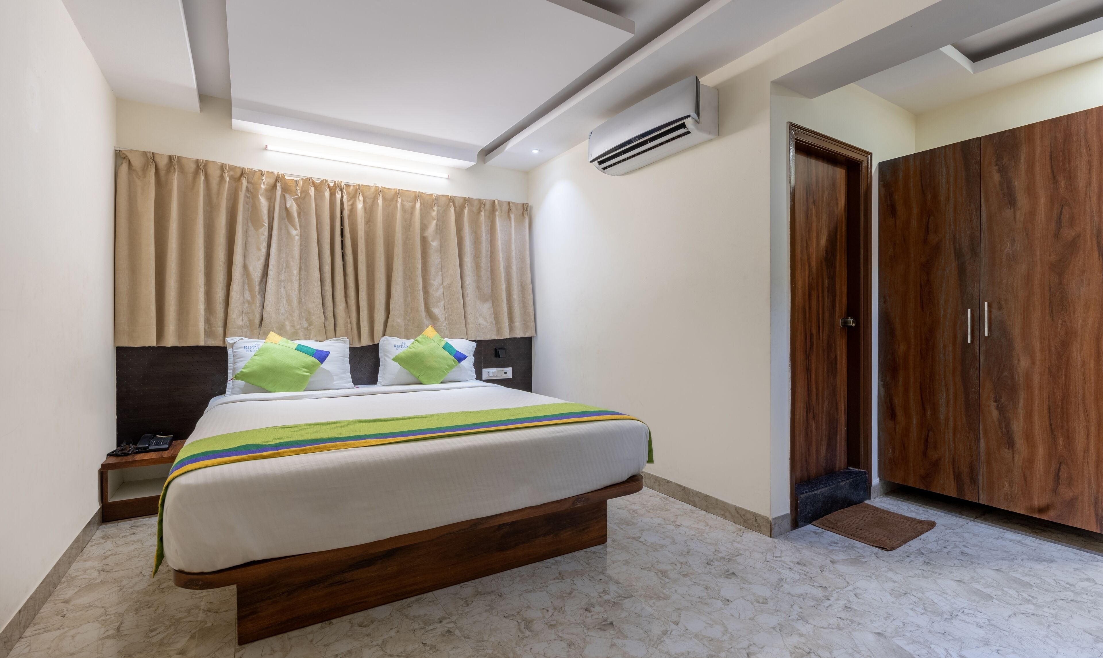 A bedroom with a bed, bedside tables, a wardrobe, and an air conditioning unit.
