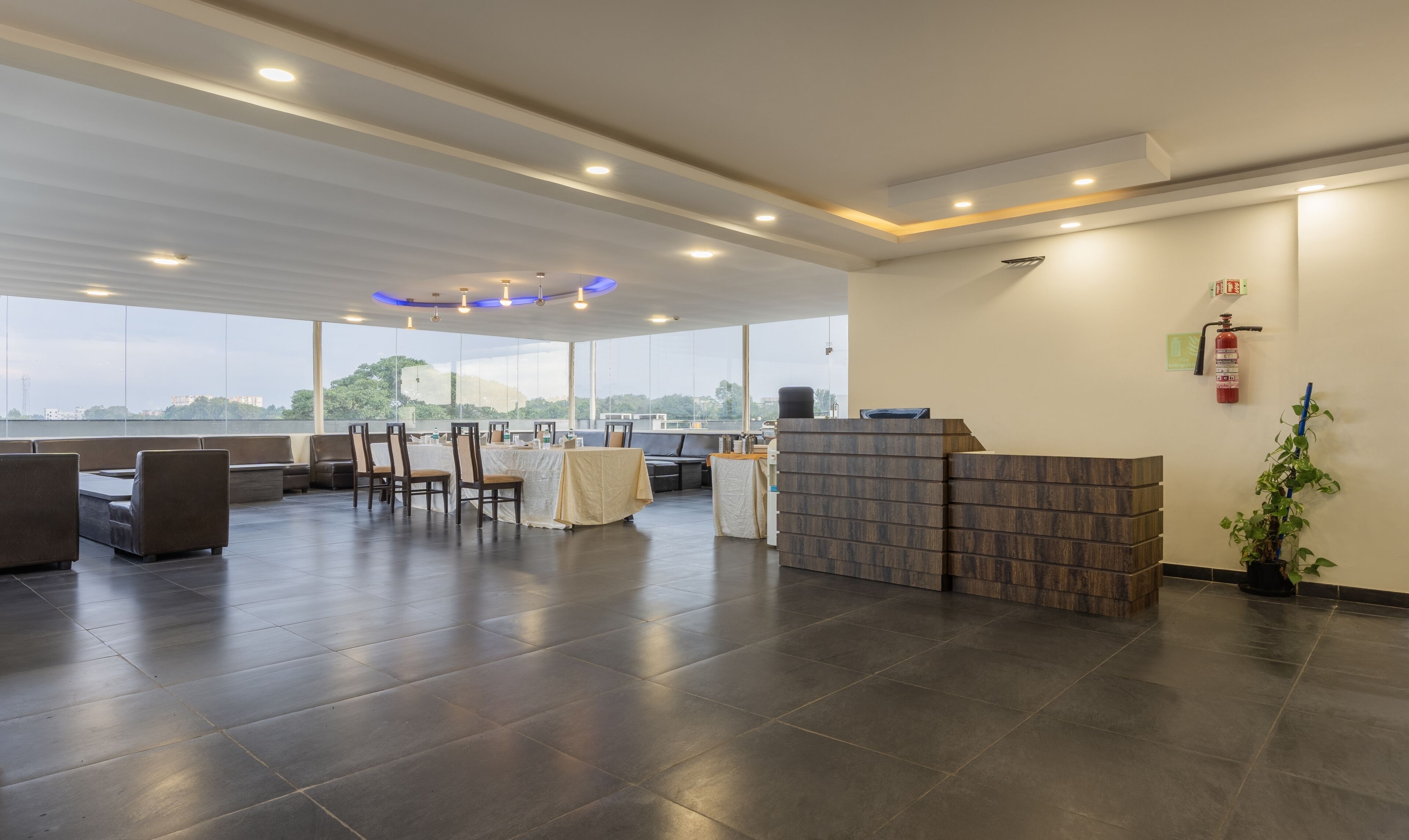 A spacious indoor area with a reception desk, seating arrangements, and large windows offering a view of the outdoors.