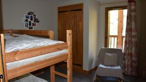 A bedroom with a wooden bunk bed, a small table with a chair, a wooden wardrobe, and a door leading to a balcony. - 3rd floor, balcony, fireplace or stove, tv, 110m², Pralognan-la-Vanoise (Pralognan-la-Vanoise)