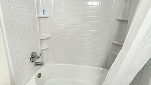 Un baño moderno con una bañera independiente, paredes cubiertas de azulejos blancos y una cortina de ducha.