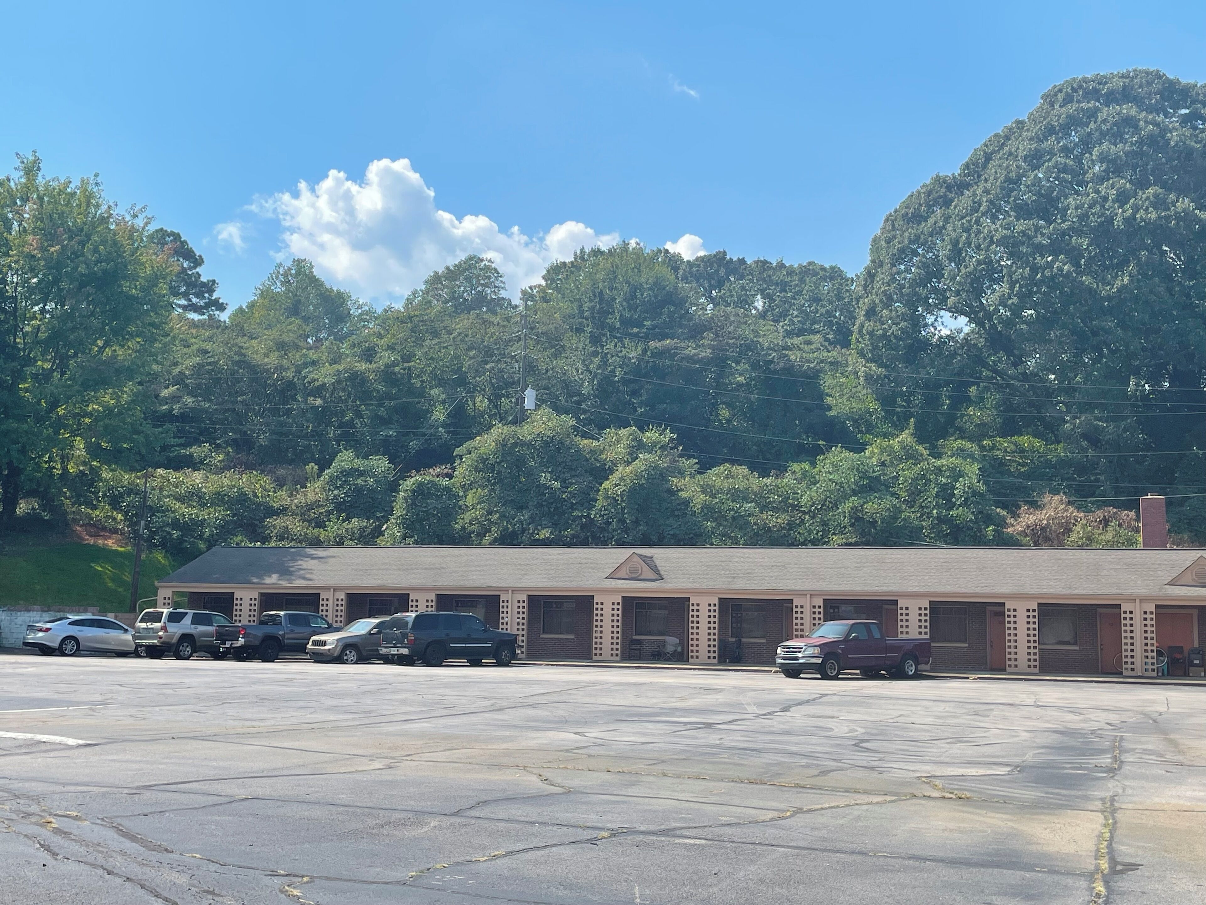 A parking lot with several cars parked in front of a building with a brick facade and a flat roof.