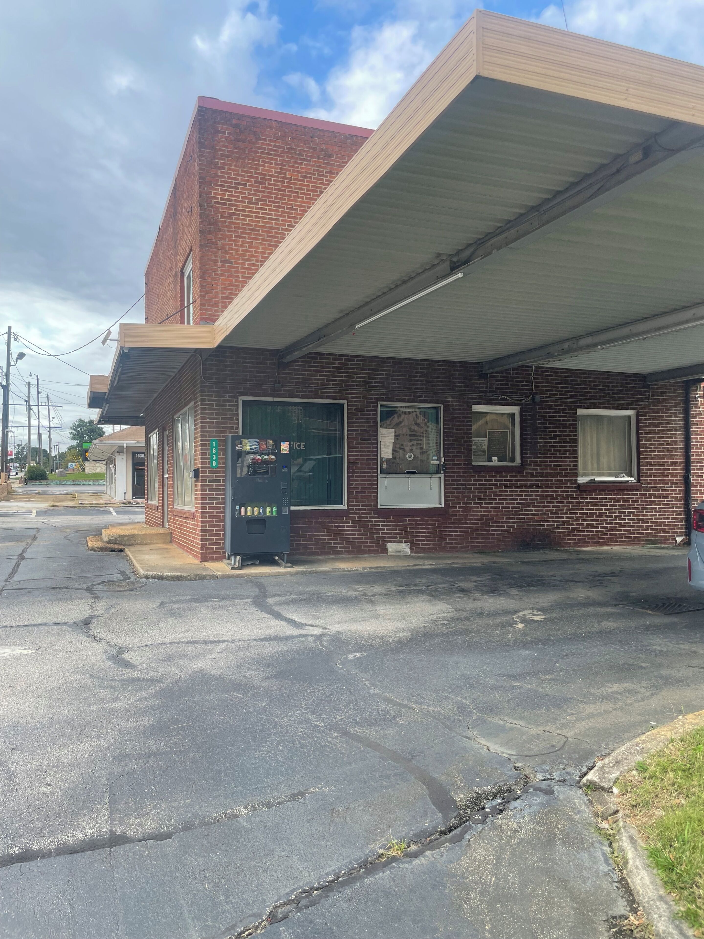 A two-story brick building with a flat roof and a covered parking area.