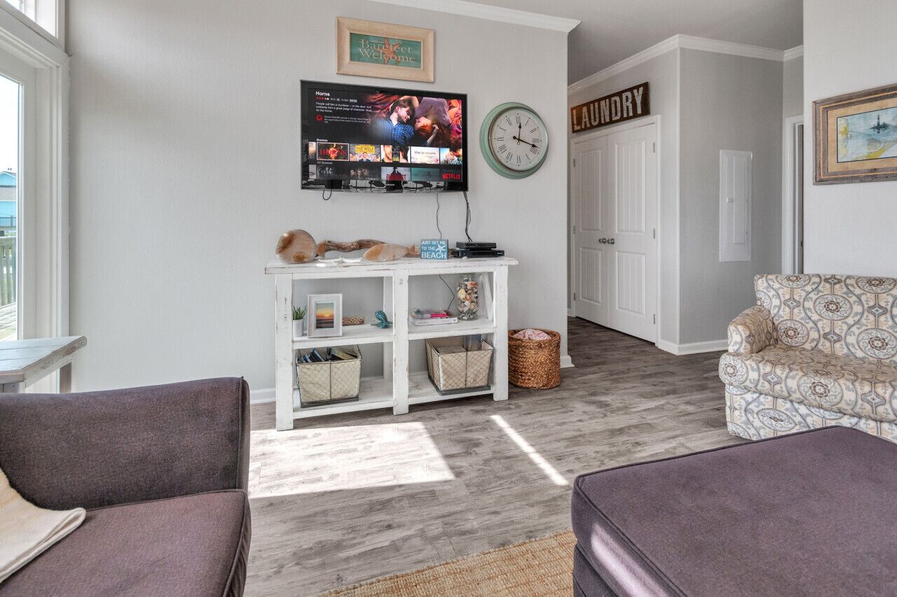 A living room with a TV, a clock, a sofa, and a patterned armchair.