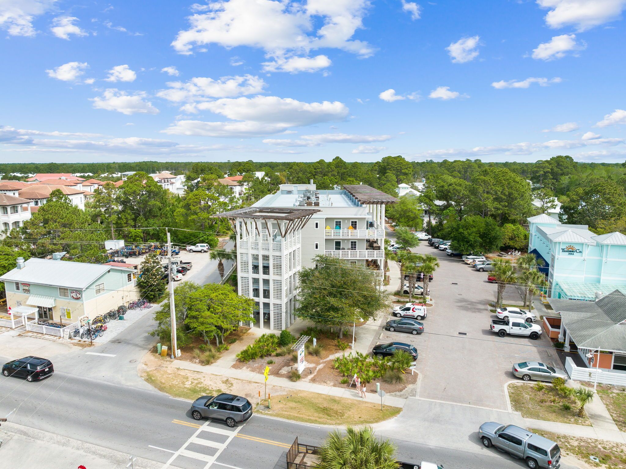 A multi-story hotel with a central courtyard, surrounded by parked cars and a clear sky.