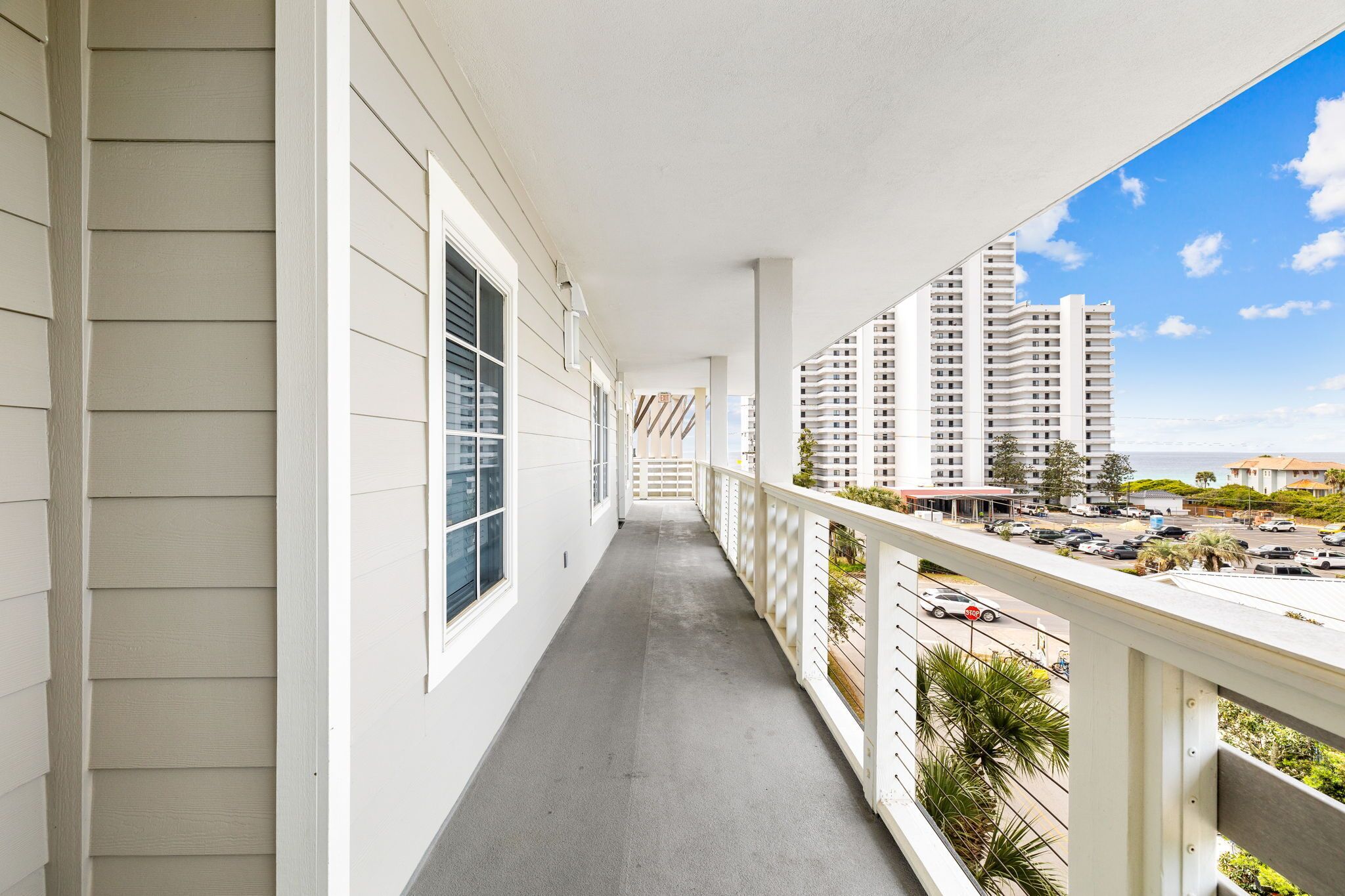 A balcony with a view of a parking lot and high-rise buildings.