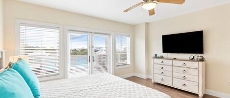 A bedroom with a bed, a ceiling fan, a TV, and a dresser.
