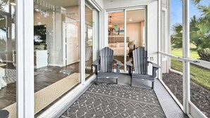A modern hotel room with a large sliding glass door leading to a balcony, a bed, a desk, and a chair. - Naples lake view condo at Lely golf resort! (Naples)