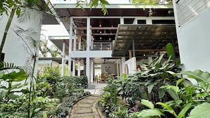 A modern building with a covered outdoor area, stone pathway, and lush greenery. - Nereus Retreats (Puerto Jiménez)