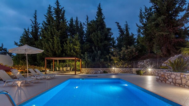 A swimming pool with lounge chairs and a pergola, surrounded by trees and stone walls. - Villa Giorgos - Villa with private pool (Ágios Pávlos)