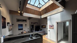 A modern kitchen with a skylight, wooden beams, and a large island. - “The Roost” downtown Red Lodge, MT (Red Lodge)