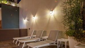 A sunlit outdoor seating area with lounge chairs and wall-mounted lights. - Casa Adefra Boutique Hotel Zona Colonial (Santo Domingo)