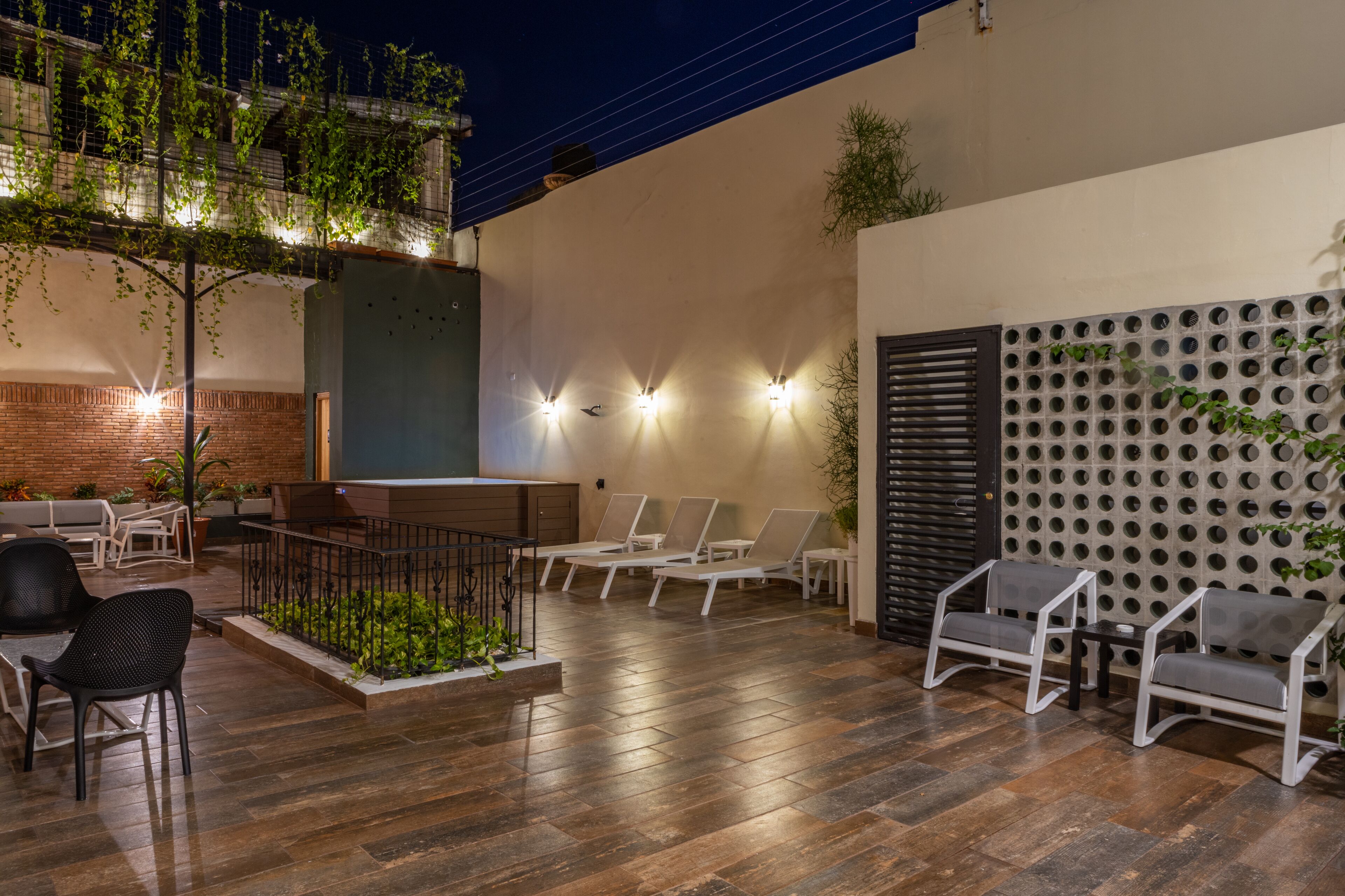 An outdoor patio with wooden flooring, seating areas, and wall-mounted lights.