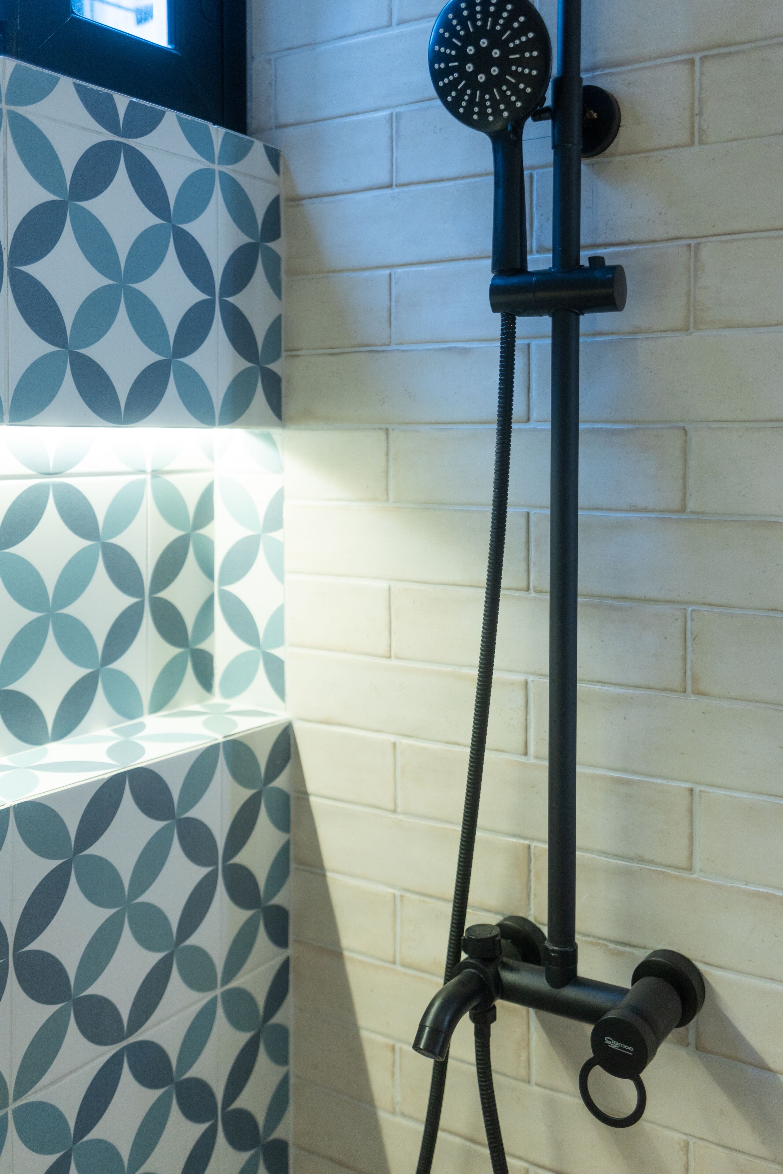 A shower with a handheld head, a flexible hose, and a wall-mounted control.