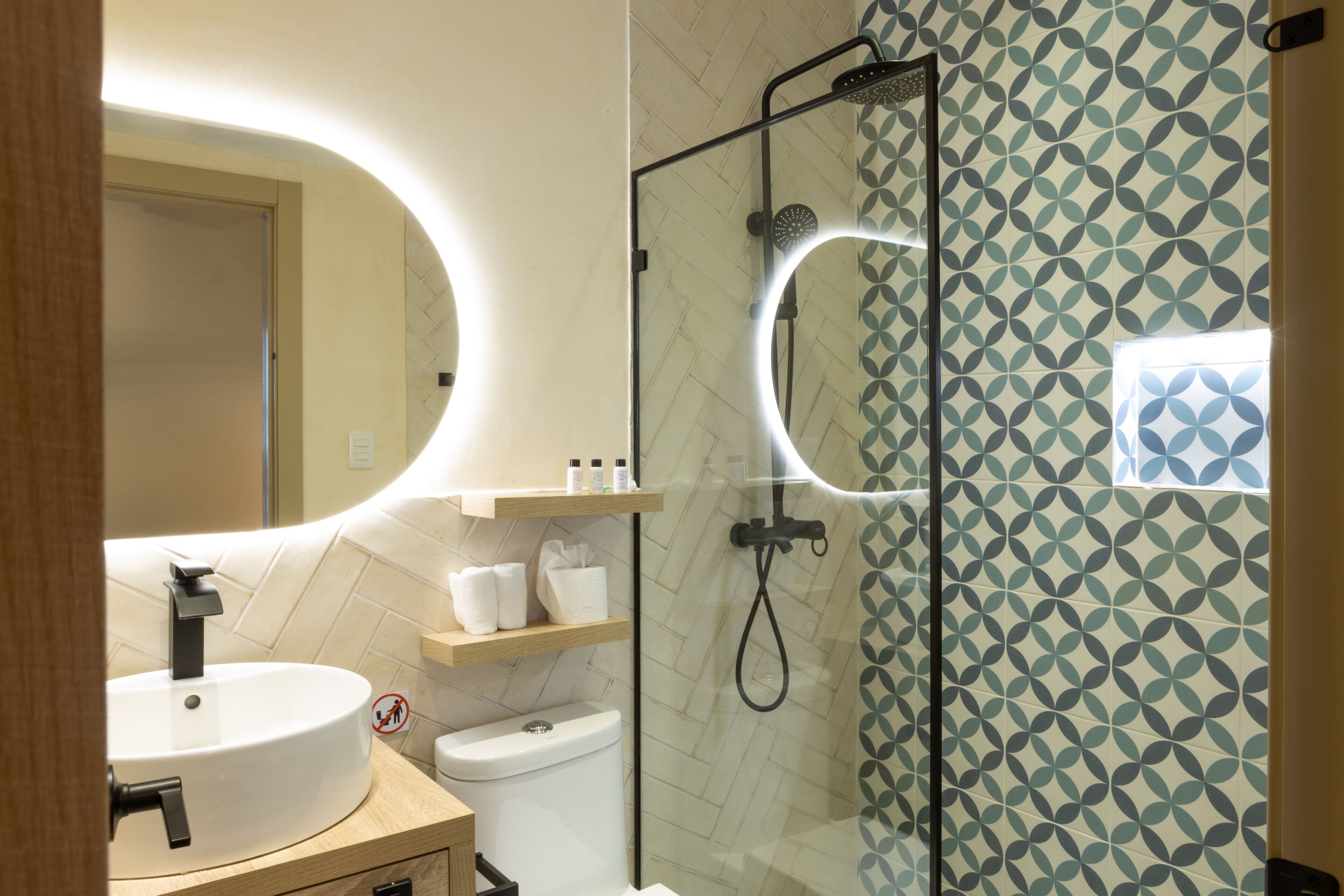 A modern bathroom with a round sink, a toilet, and a glass-enclosed shower area.