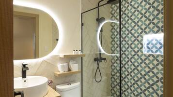 A modern bathroom with a round sink, a toilet, and a glass-enclosed shower area.