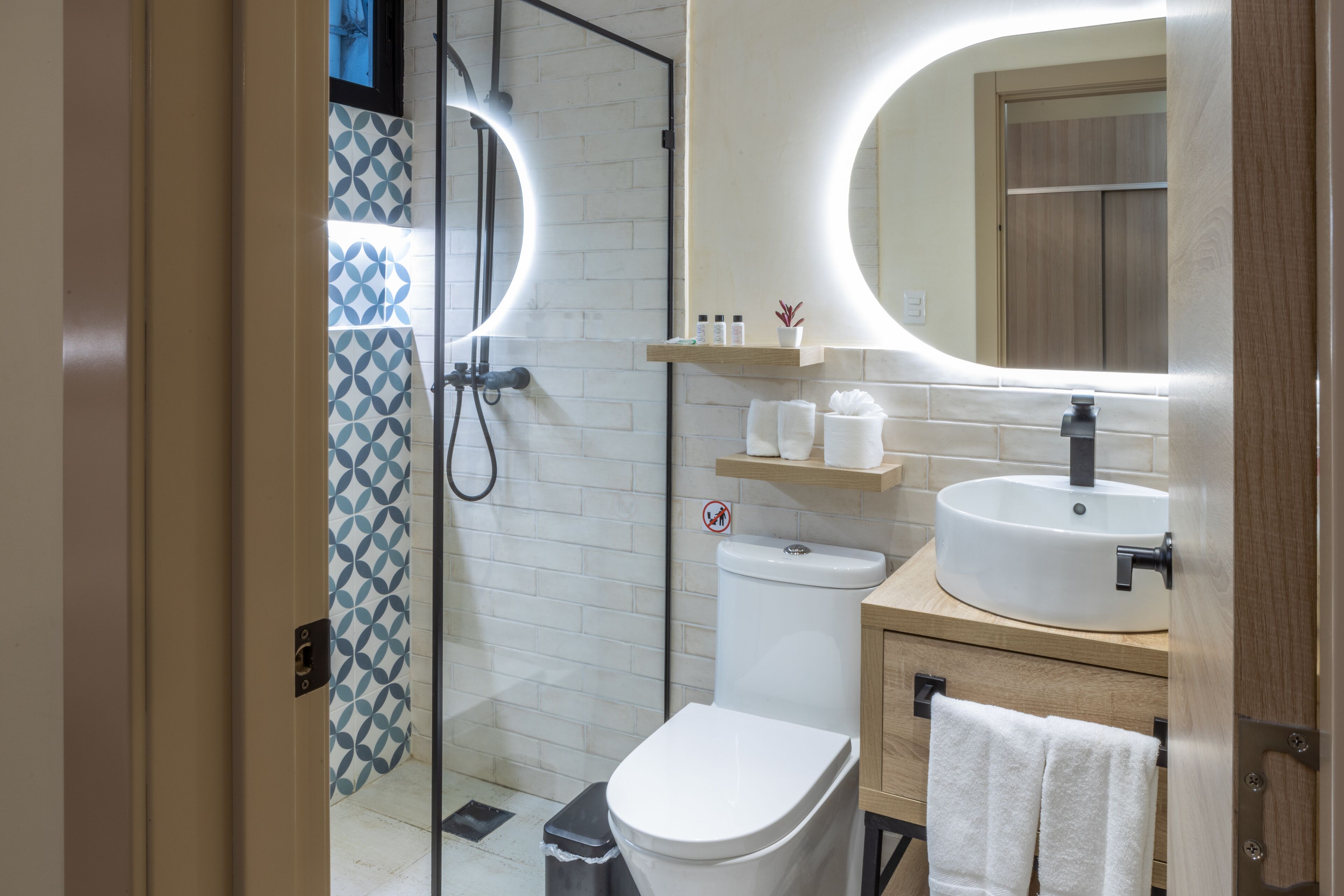 A modern bathroom with a glass shower enclosure, a white toilet, a sink with a mirror, and a towel rack.