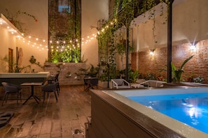 An indoor pool area with a brick wall, string lights, and lounge chairs. - Casa Adefra Boutique Hotel Zona Colonial (Santo Domingo)
