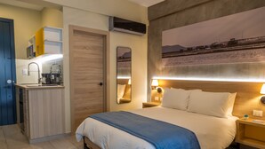 A hotel room with a bed, bedside tables, a small kitchen area, and a large window with a view of a landscape. - Casa Adefra Boutique Hotel Zona Colonial (Santo Domingo)