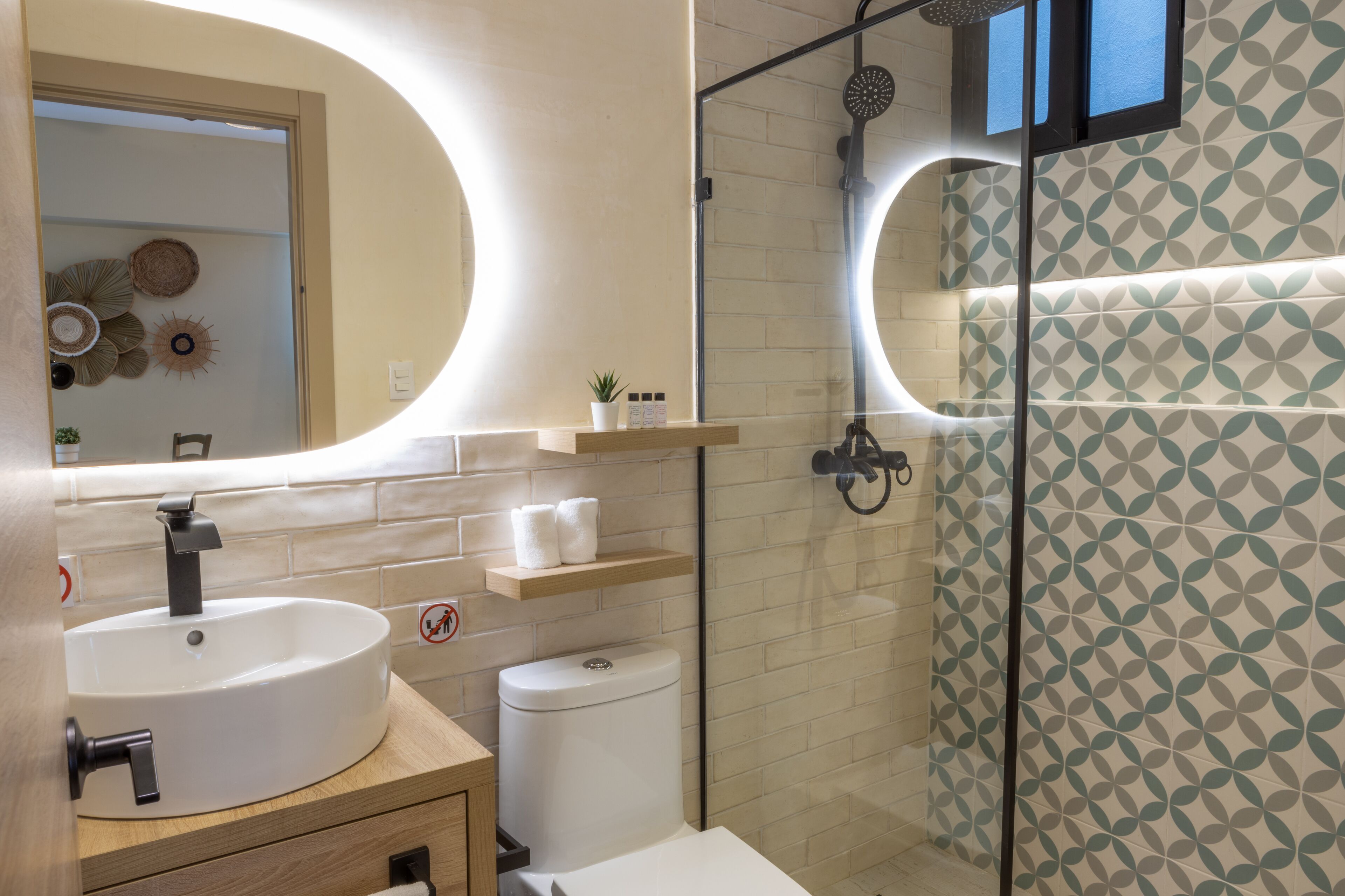 A modern bathroom with a round sink, a toilet, and a glass shower enclosure.