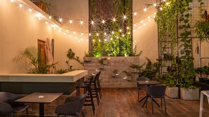 An outdoor dining area with string lights, tables, chairs, and potted plants. - Casa Adefra Boutique Hotel Zona Colonial (Santo Domingo)