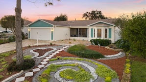 A single-story house with a garage, a driveway, and a landscaped garden with a spiral pattern.