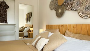 A bedroom with a wooden headboard, beige bedding, and a mirror reflecting the room. - Rosa Atlantic Apartment (Corralejo)