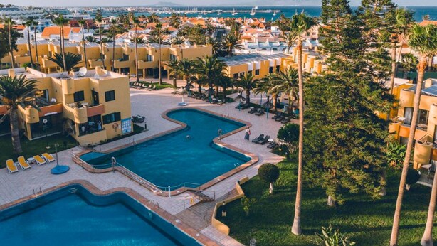 A resort with multiple swimming pools, palm trees, and a view of the sea. - Rosa Atlantic Apartment (Corralejo)