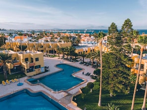 Resort com várias piscinas, palmeiras e vista para o mar.