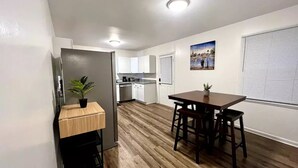 A compact kitchen with white cabinets, a wooden countertop, and a small dining area with a table and chairs.