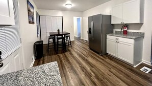 A compact kitchen with a refrigerator, a dining table with chairs, and a small countertop.