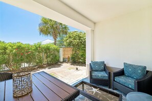 An outdoor patio with wicker furniture, a starfish decoration, and a view of a garden with a wooden fence and palm tree. - Walk to Rosemary Beach w/ Pool. Ground Floor (Panama City Beach)