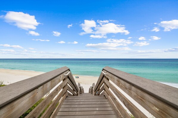 A wooden staircase leading to a beach with a clear sky.