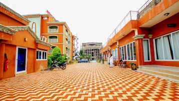 A hotel courtyard with a patterned brick floor, a fire extinguisher, and a motorcycle parked on the left.