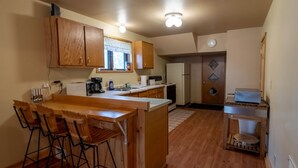 A compact kitchen with wooden cabinets, a bar area, and a refrigerator. - Come explore the Western UP! Located right on the atv and snowmobile trail. (Ewen)