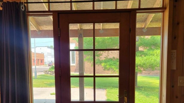 A wooden interior with a sliding glass door leading to a deck. - Come explore the Western UP! Located right on the atv and snowmobile trail. (Ewen)