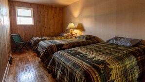 A room with two beds, a chair, a lamp, and a window. - Come explore the Western UP! Located right on the atv and snowmobile trail. (Ewen)