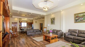 Un vaste espace de vie doté d’un plancher en bois, d’un grand canapé, d’une table basse et d’une table à manger.